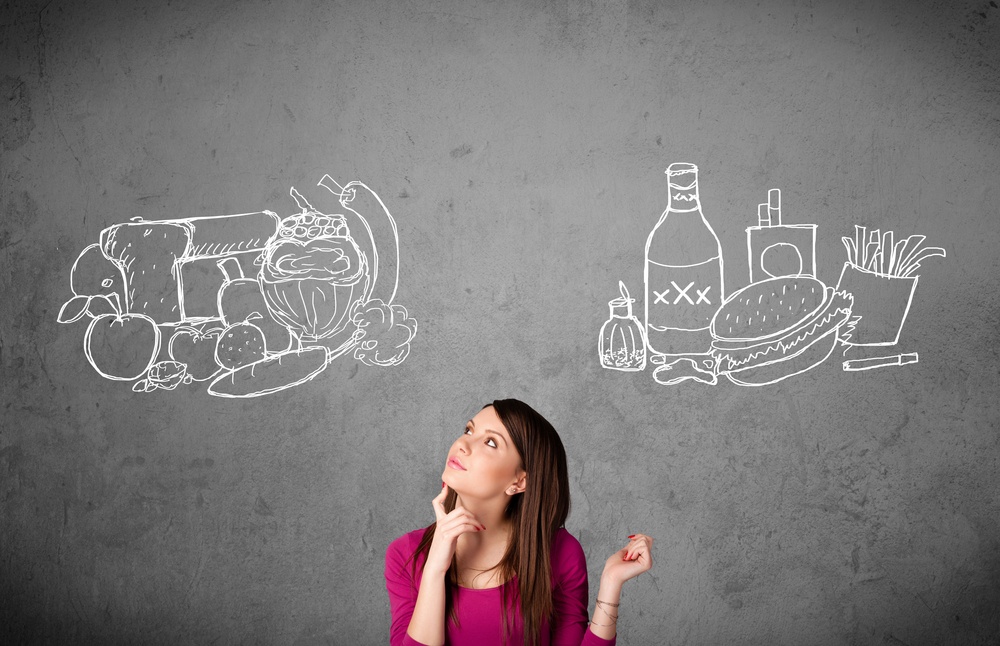 Pretty young woman choosing between healthy and unhealthy foods