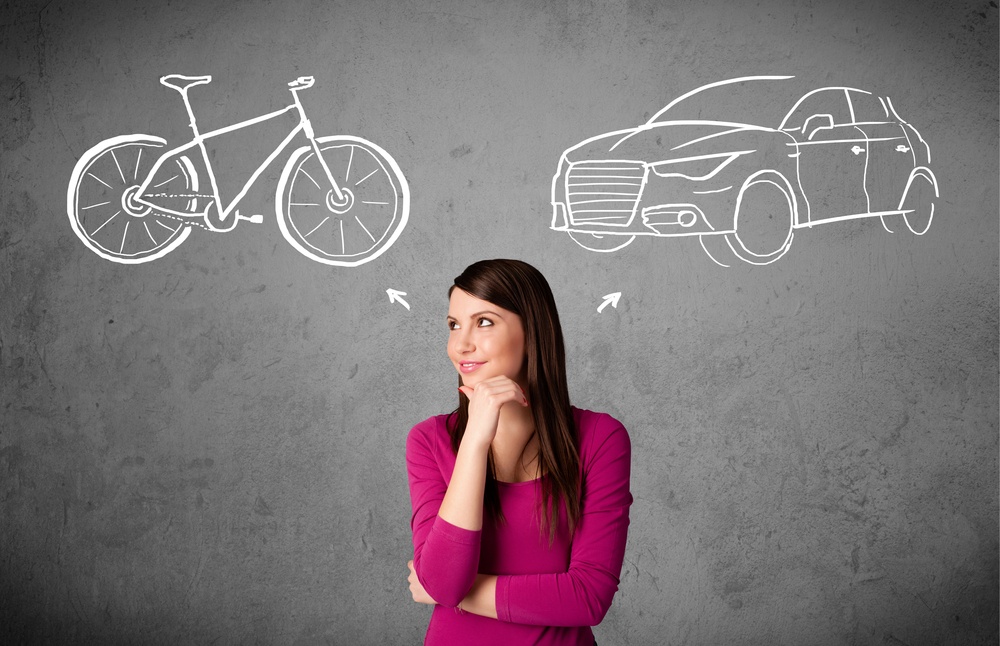 Pretty young woman taking a decision between bicycle and car